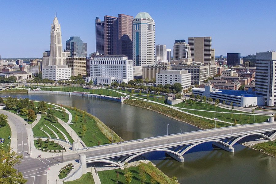 Contact - Aerial View of Columbus Ohio Skyline Displaying Many Tall Buildings, a Bridge That Crosses Over a Large River on a Bright Clear Day